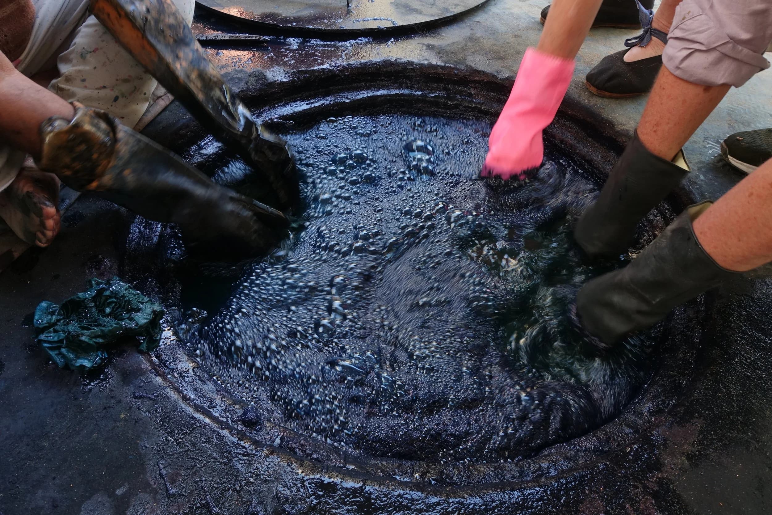 Hands dipping fabric into indigo vat