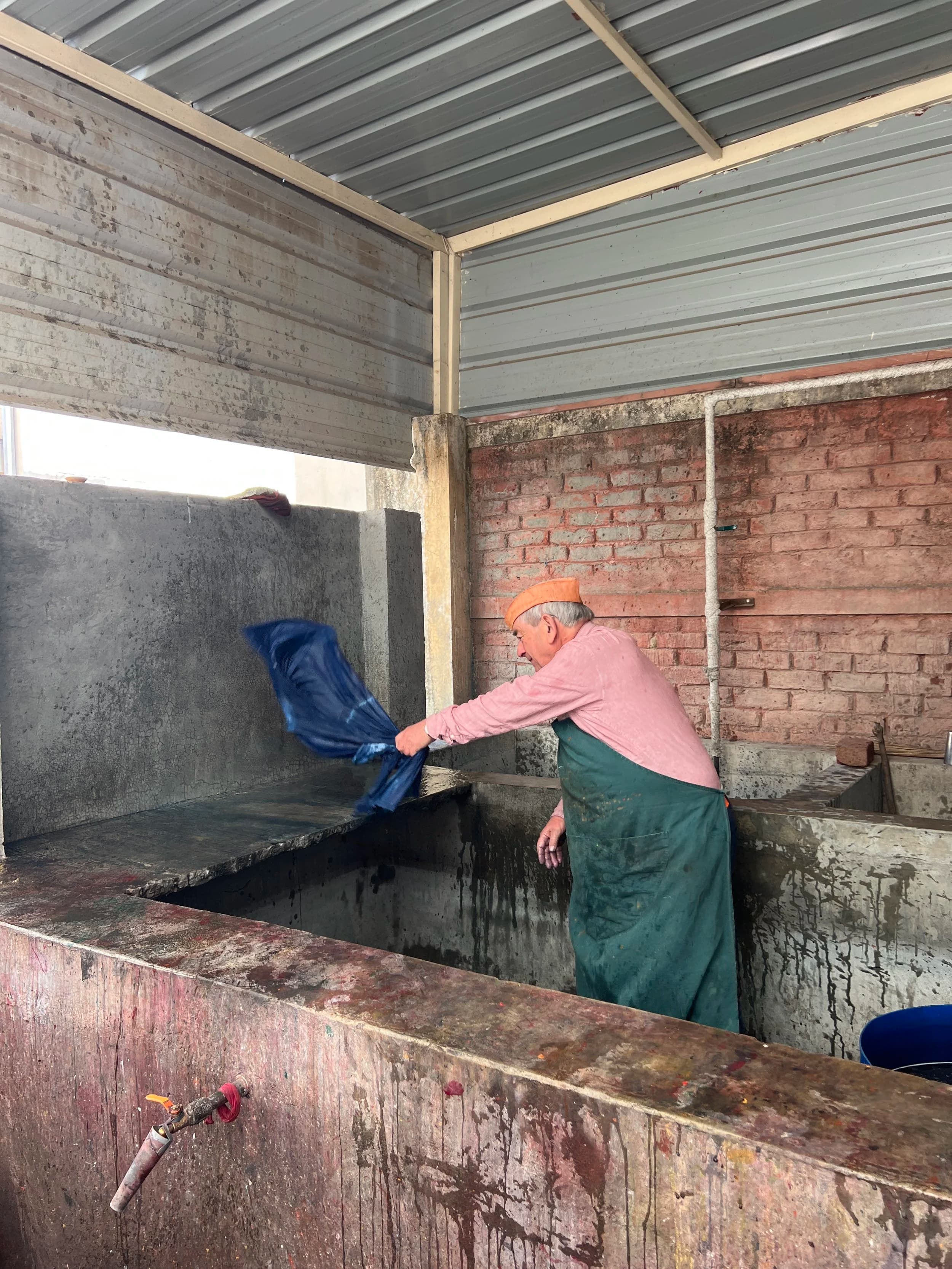 Elderly artisan pulling fabric from tank