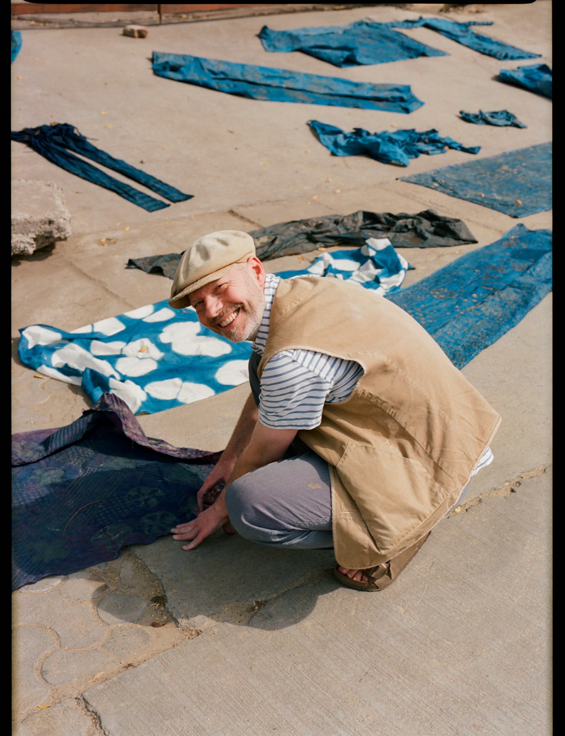 Artisan smiling with fabrics drying on rooftop